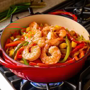 large red pan le creusset dutch oven style, tan color inside the pan, on a gas stove, with olive oil, reduced fully cooked diced onions and red, green